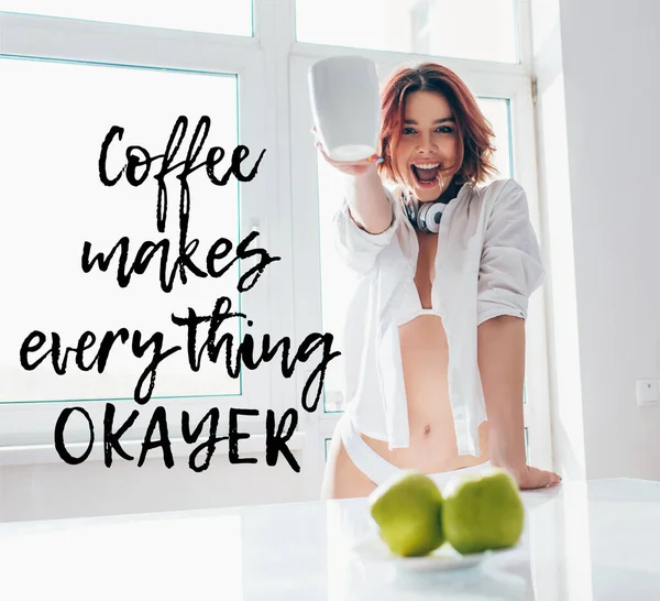 Menina animado tomando café para o café da manhã durante o auto-isolamento com café faz cada coisa okayer letras — Fotografia de Stock