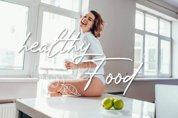 Fröhliches Mädchen mit einer Tasse Kaffee auf der Küche mit Äpfeln in der Selbstisolierung mit gesundem Essen Schriftzug — Stockfoto
