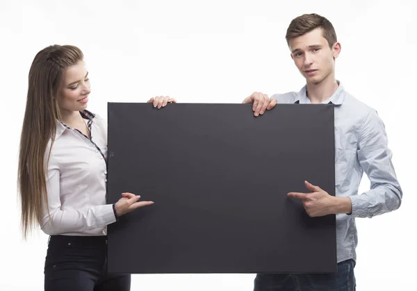 Joven feliz pareja mostrando la presentación señalando en el cartel sobre — Foto de Stock