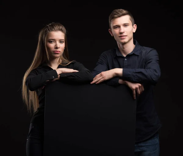 Jeune couple heureux montrant la présentation pointant sur la plaque — Photo