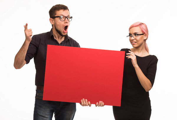 Young surprised couple showing presentation pointing placard