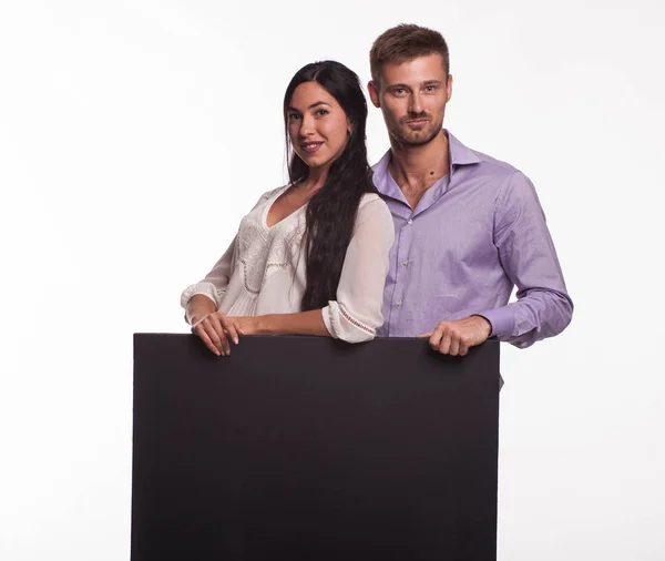 Jovem casal feliz mostrando apresentação apontando cartaz — Fotografia de Stock