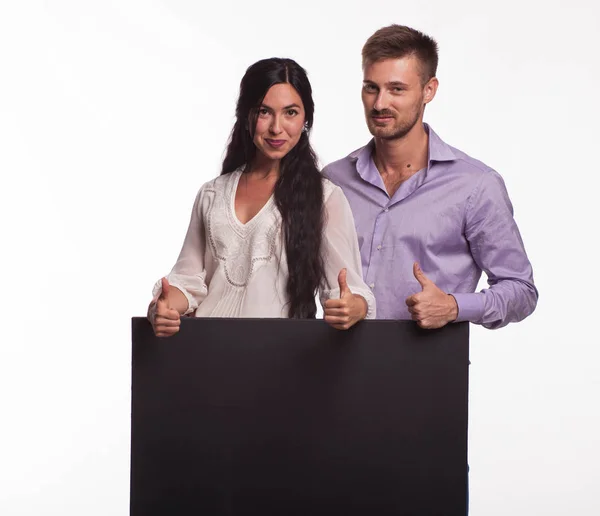 Giovane coppia felice mostrando presentazione puntando cartello — Foto Stock