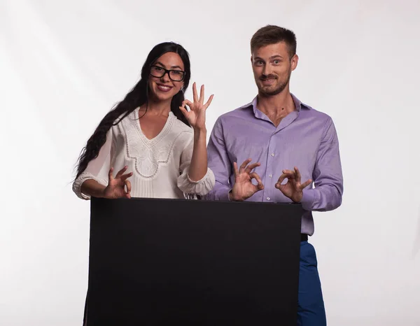 Joven feliz pareja mostrando presentación señalando cartel —  Fotos de Stock