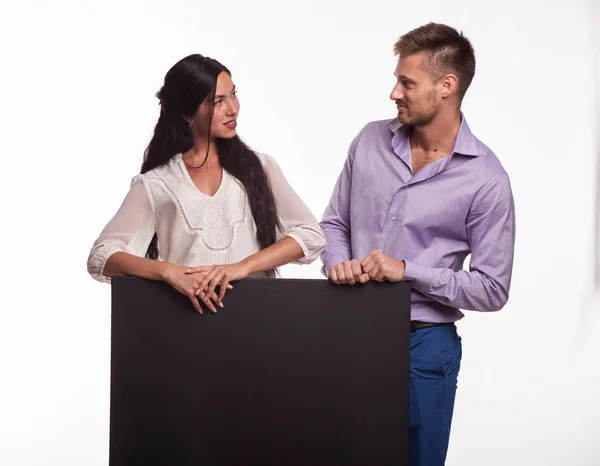 Young surprised couple showing presentation pointing placard — Stock Photo, Image