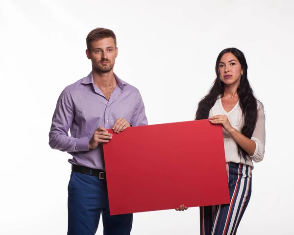 Giovane coppia pensierosa mostra presentazione puntando cartello — Foto Stock