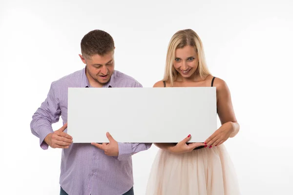 Joven pareja sorprendida mostrando la presentación señalando cartel . — Foto de Stock