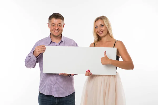 Joven feliz pareja mostrando presentación señalando cartel . — Foto de Stock