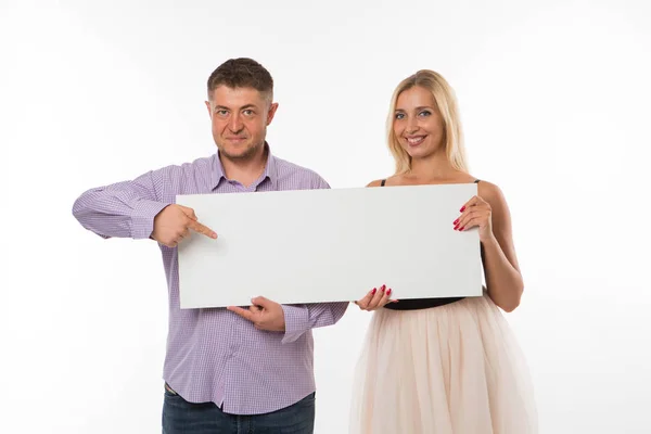 Joven feliz pareja mostrando presentación señalando cartel . — Foto de Stock