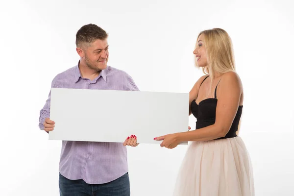 Young jocular couple showing presentation pointing placard. — Stock Photo, Image