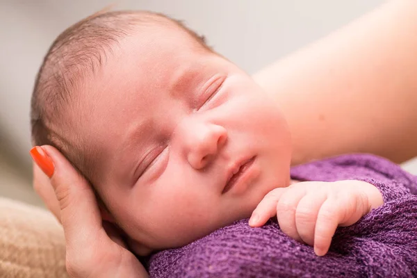 Sleeping newborn baby girl in a violet knit baby blanket. — Stock Photo, Image