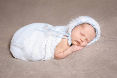 Yavaşça mavi örgü şapkalı uyuyan bebek kız.