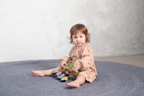 Liten glad tjej leker med leksak på golvet. — Stockfoto