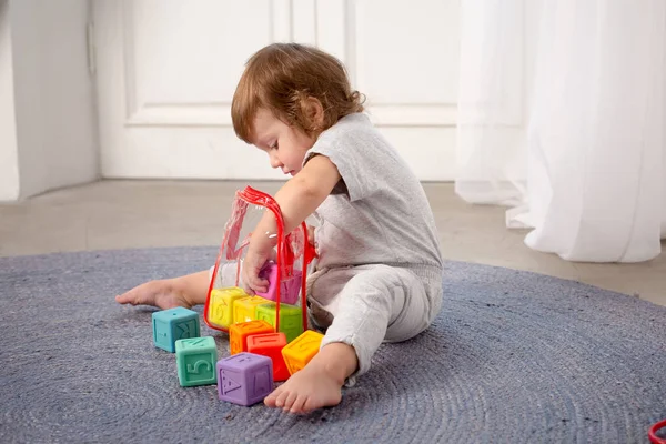 Маленькая счастливая девочка играет с игрушкой на полу . — стоковое фото