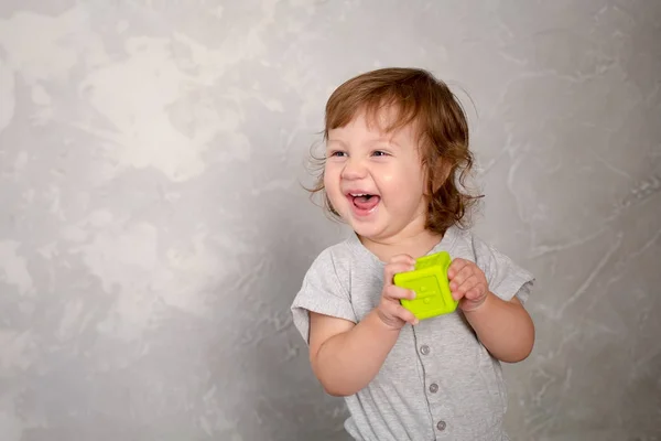 灰色の壁の背景におもちゃで遊ぶ女の子. — ストック写真