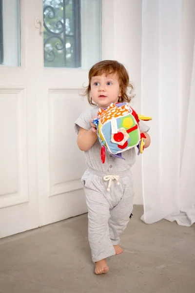 白い扉の背景におもちゃで遊ぶ奇妙な少女. — ストック写真