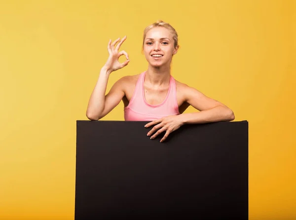 Joven mujer alegre mostrando la presentación, señalando en el cartel — Foto de Stock