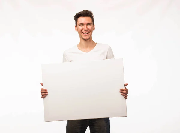 Jovem homem alegre mostrando apresentação, apontando no cartaz . — Fotografia de Stock