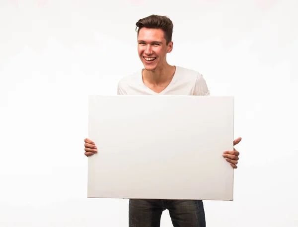 Jovem homem alegre mostrando apresentação, apontando no cartaz . — Fotografia de Stock