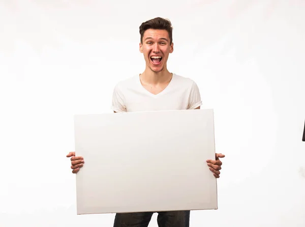Jovem homem alegre mostrando apresentação, apontando no cartaz . — Fotografia de Stock