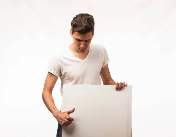 Jovem homem pensativo mostrando apresentação, apontando no cartaz . — Fotografia de Stock