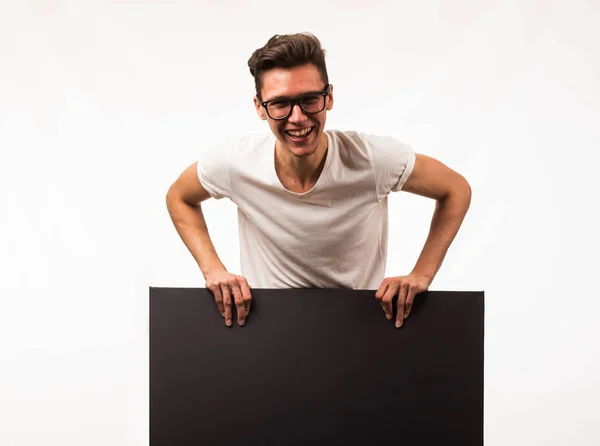 Jovem homem alegre mostrando apresentação, apontando no cartaz . — Fotografia de Stock