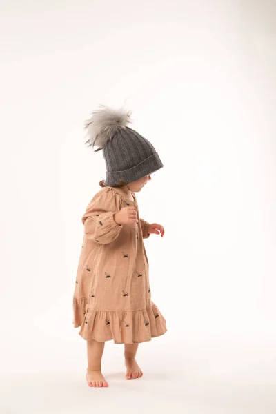 Menina bonito no vestido bege em um chapéu cinza isolado no fundo branco . — Fotografia de Stock