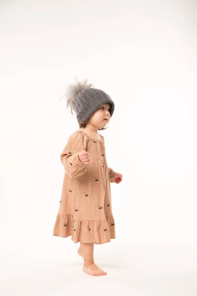 白い背景に分離されたグレーの帽子にベージュのドレスでかわいい女の子. — ストック写真