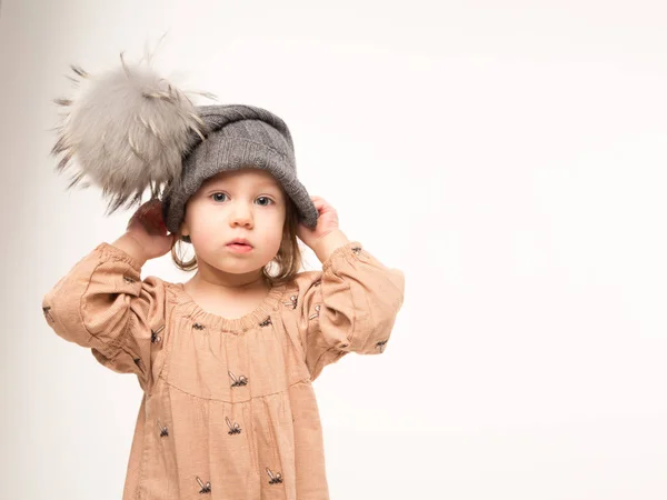 Egy elszigetelt fehér background szürke kalap bézs ruha aranyos kislány. — Stock Fotó