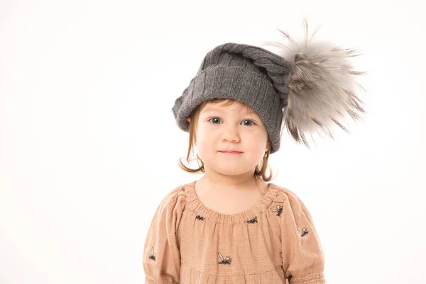 Carino bambina in abito beige in un cappello grigio isolato su sfondo bianco . Immagine Stock