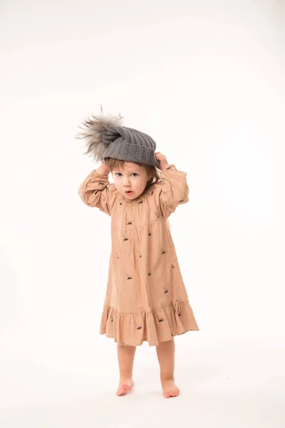 Menina bonito no vestido bege em um chapéu cinza isolado no fundo branco . — Fotografia de Stock