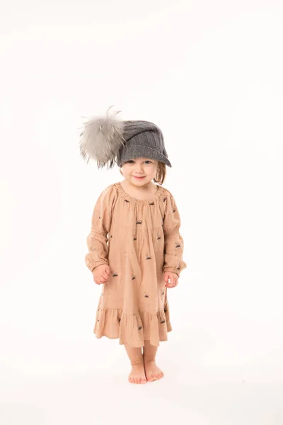 Linda niña en vestido beige en un sombrero gris aislado sobre fondo blanco . — Foto de Stock