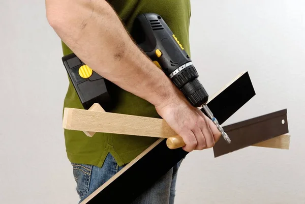 Un hombre con un destornillador inalámbrico y madera en la mano — Foto de Stock