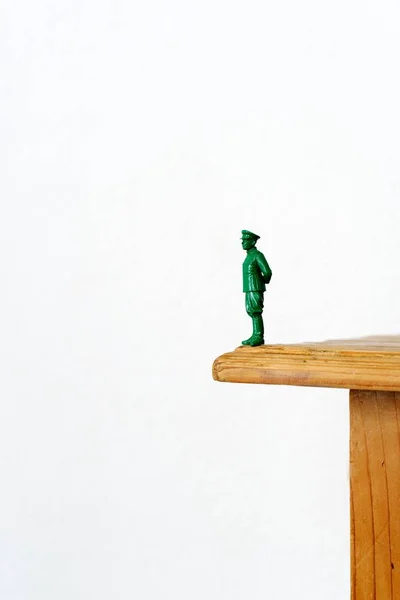 En plast soldat som står på en patronhylsa, på bottentyg trä — Stockfoto
