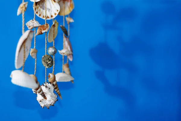 スティックに青色の背景に殻を持つ風鈴 — ストック写真
