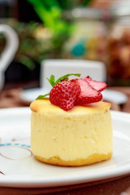 Beyaz tabakta yabanmersinli cheesecake.