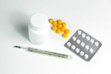 İlaç ve termometresi olan beyaz plastik kutu.