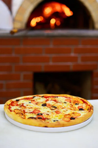 Φρεσκομαγειρεμένη Πίτσα Στο Φόντο Μιας Κουζίνας Και Μιας Φωτιάς — Φωτογραφία Αρχείου