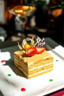 Napolyon keki, bir tabakta meyve ve ahşap bir masada çilek.