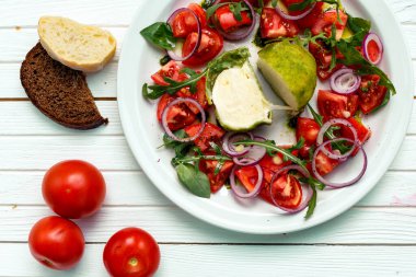 Fırında mozarella peynirli salata, ahşap bir yüzey üzerinde soğan ve domates.