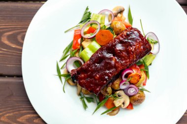 Tahta arka planda taze patates ve sulu sebzeli dana bifteği.