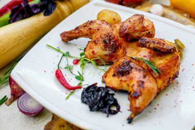 Kızarmış tavuk, soğan ve acı biberle süslenmiş bir masada.