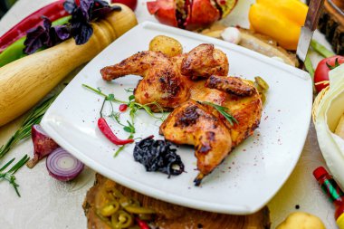 Kızarmış tavuk, soğan ve acı biberle süslenmiş bir masada.