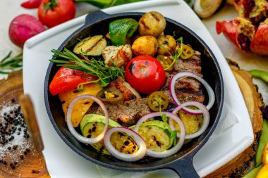 Kızartma tavasında kızarmış et, sebzeli patates ve sebzeli patates.