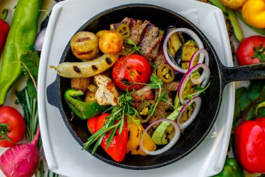 Kızartma tavasında kızarmış et, sebzeli patates ve sebzeli patates.