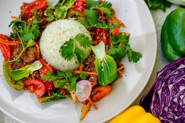 Beyaz tabakta süslü bir masada sebzeli Tayland eti.