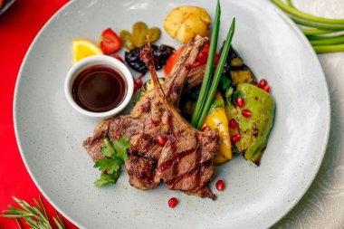 Kızarmış et, sebzeli ve soslu beyaz tabak.