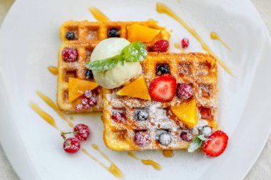 Belçika waffleları, dondurma, meyve ve meyveler beyaz tabakta.