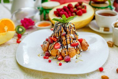 Krekembush, üzerinde çikolata ve fındık olan zarif bir Fransız profiterollü kek.