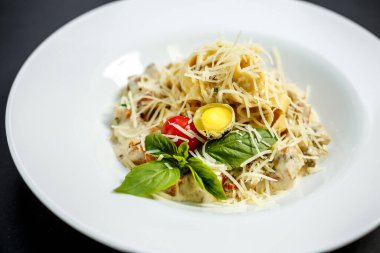 Mantarlı ve peynirli makarna, krema soslu bıldırcın yumurtası ve domates, izole edilmiş.